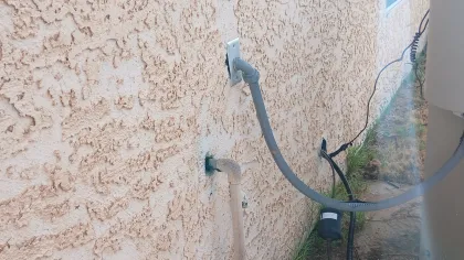 Bee inspection of stucco wall in Mohave Valley, with bees entering and exiting a plumbing penetration